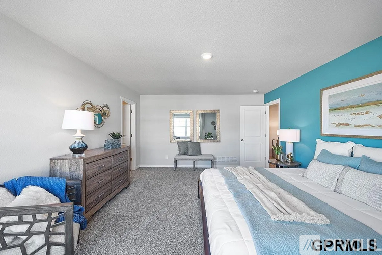 A bedroom with a large bed, a dresser, and a mirror.