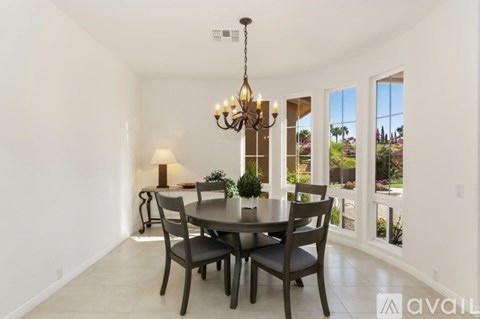 A dining room with a table set for four and a chandelier hanging from the ceiling.