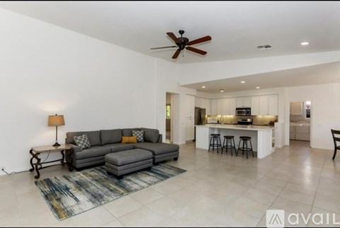 A living room with a grey couch and a ceiling fan.