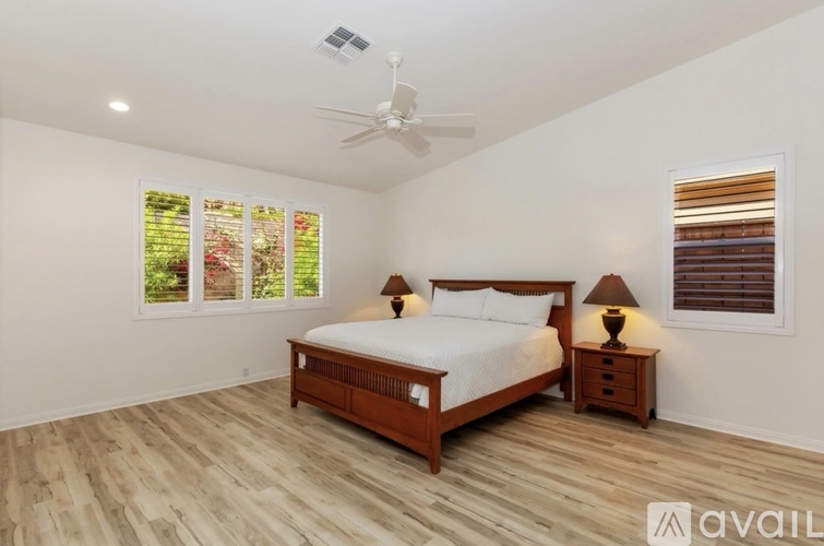 A bedroom with a bed, two lamps, and a ceiling fan.
