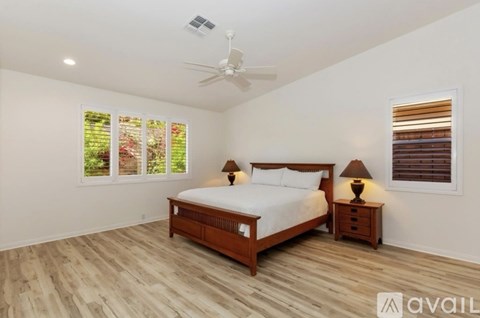 A bedroom with a bed, two lamps, and a ceiling fan.