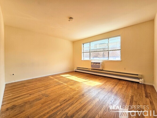 A room with wooden floors and a window with blinds.