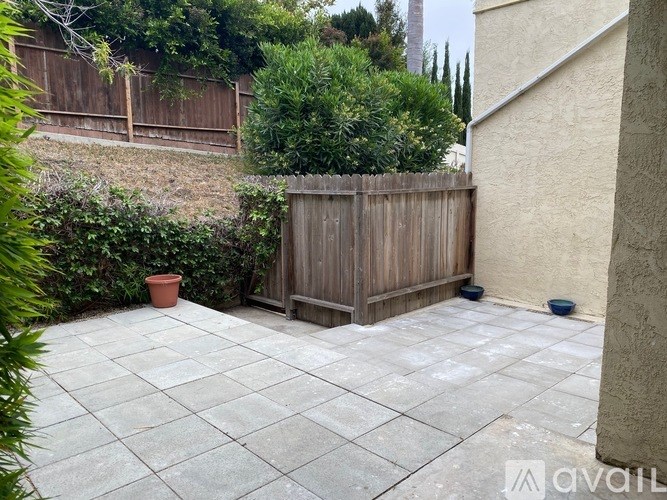 A patio with a wooden fence and a potted plant.