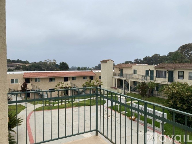 A view of a courtyard with a fence and a building in the background.