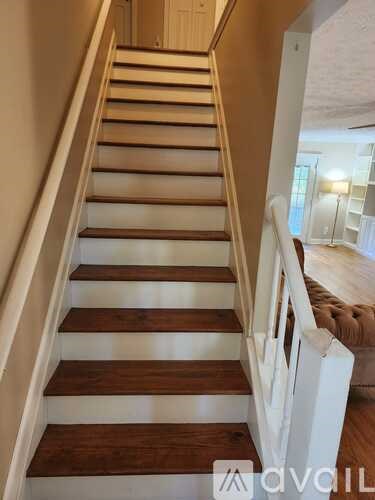 A wooden staircase with white railings leads up to a doorway.