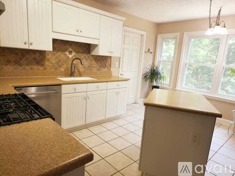 A kitchen with white cabinets and a brown countertop.