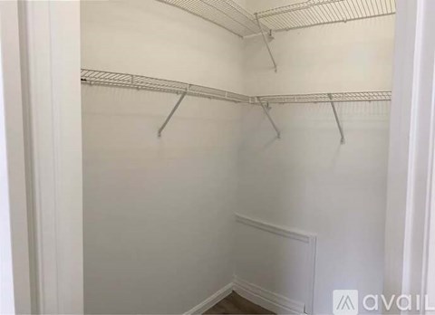 A white closet with three metal hangers.