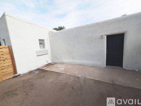 A white building with a black door and a wooden door.