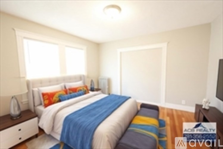 A bedroom with a bed, nightstand, and window.