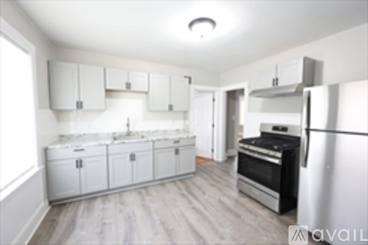 A kitchen with white cabinets and a wooden floor.