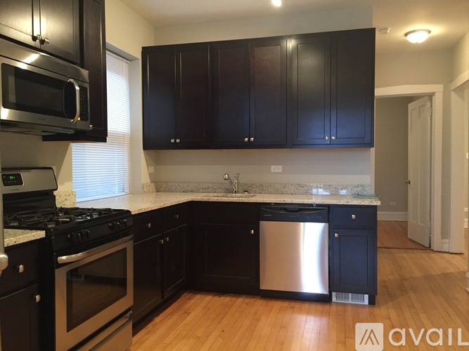A kitchen with black cabinets and a stainless steel dishwasher.