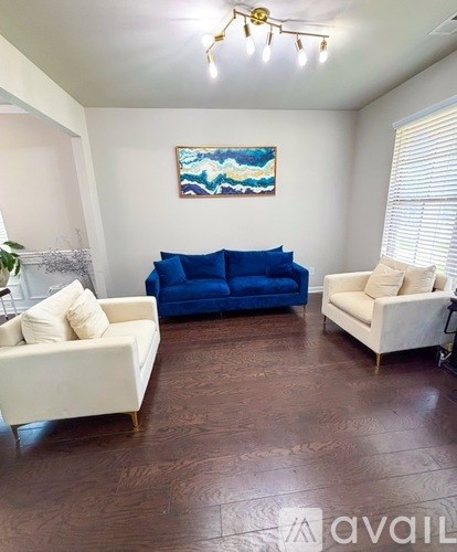A living room with a blue couch and a painting on the wall.
