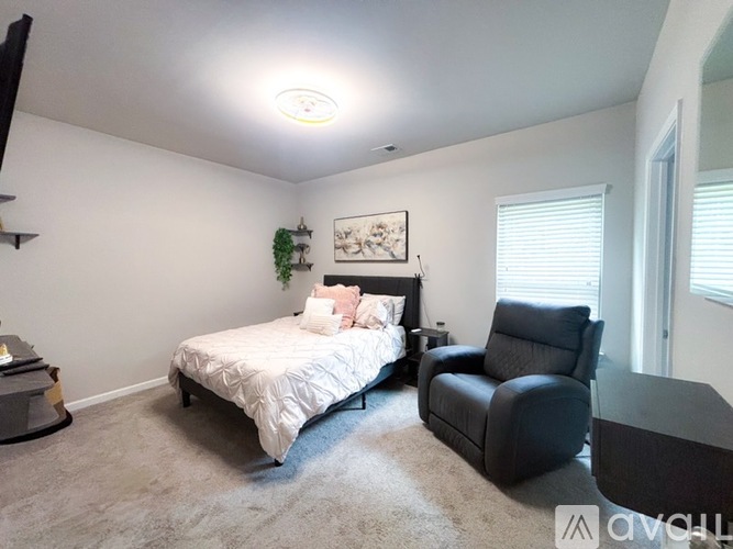 A bedroom with a bed, chair, and a plant on the wall.