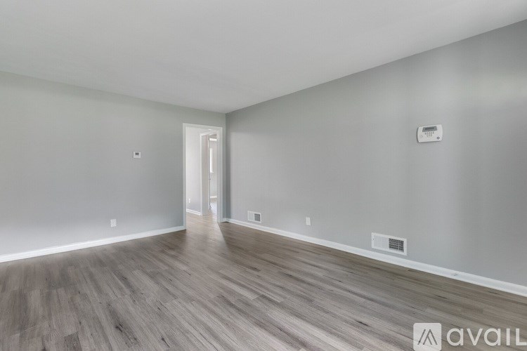 A room with wooden flooring and a doorway leading to another room.