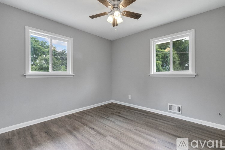 A room with a ceiling fan and two windows.