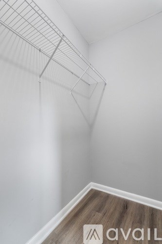 A white wall with a wooden floor and a metal rack.