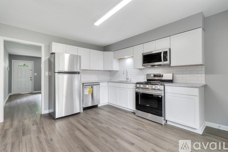 A kitchen with white cabinets and a stainless steel refrigerator.
