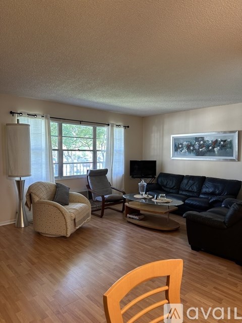A living room with a black couch, a chair, and a table with a glass on it.
