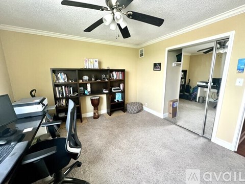 A room with a ceiling fan and a bookshelf.