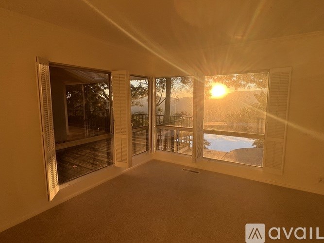 A room with a view of a sunset through the windows.