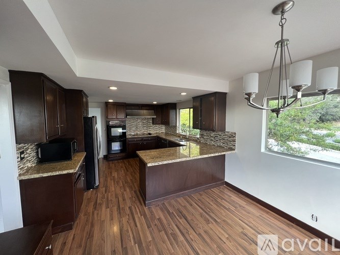 A kitchen with dark wood cabinets and a granite countertop.