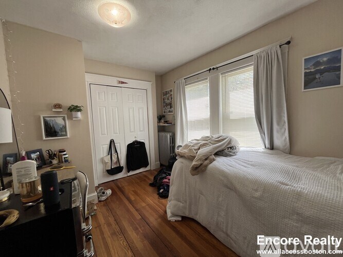 A bedroom with a bed, a window with curtains, and a door with a white frame.