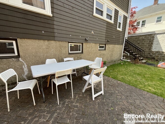 A patio with a table and chairs is set up outside a house.