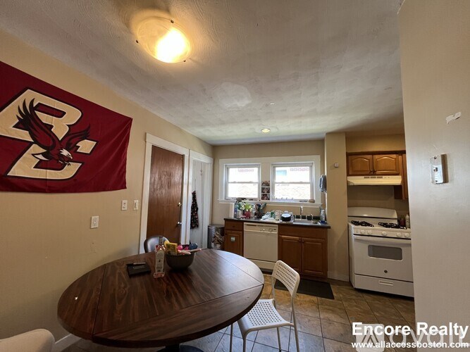 A kitchen with a table and chairs in front of a wall with a banner on it.