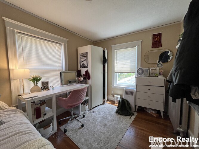 A bedroom with a desk and a chair.