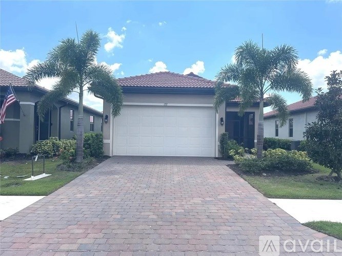 A house with a driveway and palm trees in front.