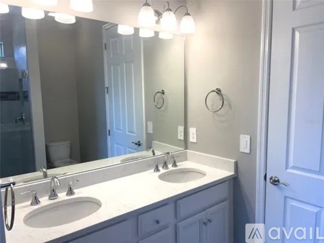 A bathroom with a double sink vanity and a mirror above it.