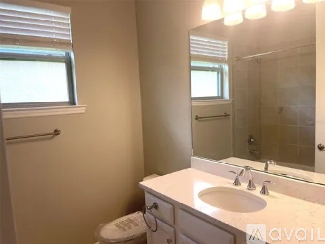 A bathroom with a toilet, sink, mirror, and a window.