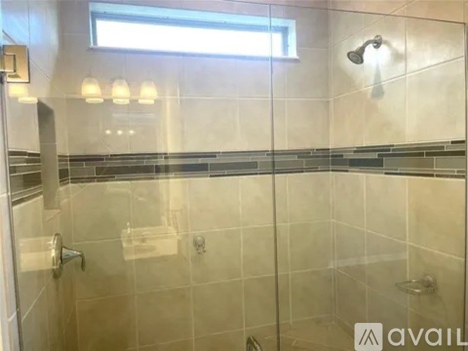 A bathroom with a glass shower stall and a window.