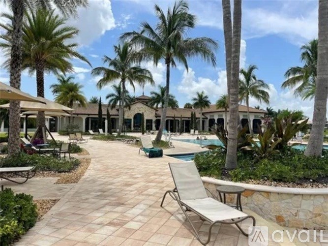 A sunny day at the poolside with palm trees and a stone wall.