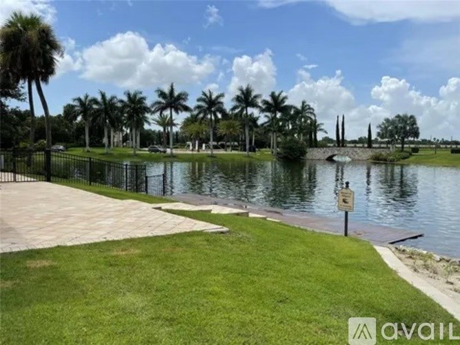 A park with a pond, palm trees and a sign.