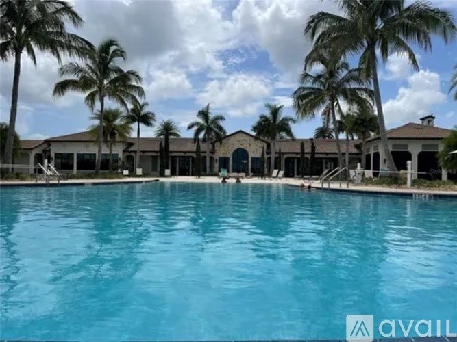 A large swimming pool in front of a building with palm trees.