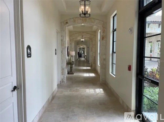 A long, narrow hallway with a chandelier and doors on the left.