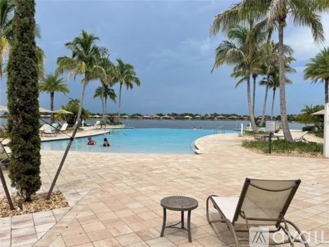 A pool surrounded by palm trees and a chair.