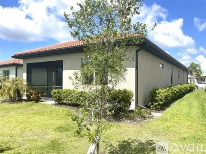 A small building with a red roof and a tree in front of it.