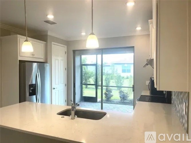 A modern kitchen with a large island and pendant lights.
