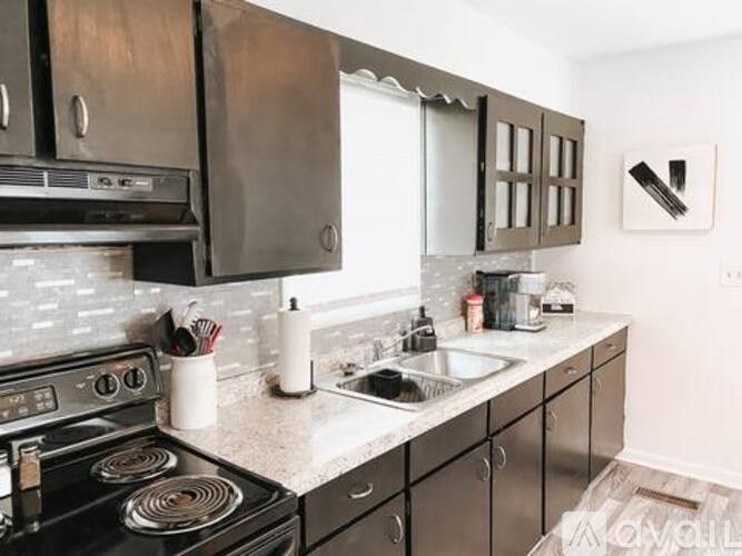 A kitchen with a stove, sink, and cabinets.