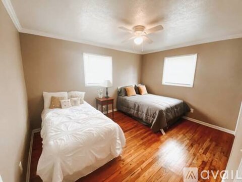 A bedroom with two beds and a ceiling fan.