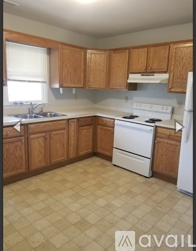 A kitchen with wooden cabinets and a white stove top oven.