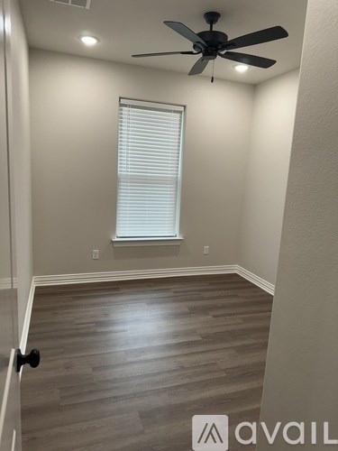 A room with a ceiling fan and a window with blinds.