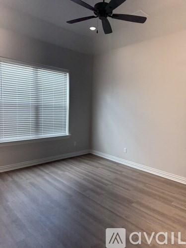 A room with a ceiling fan and a window with blinds.