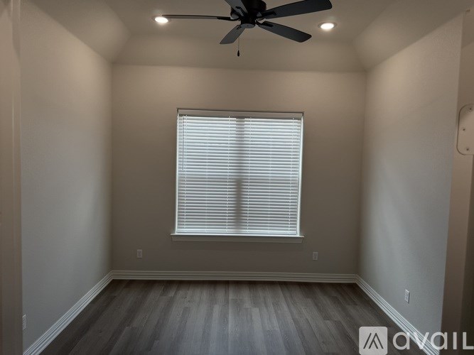 A room with a ceiling fan and a window with blinds.