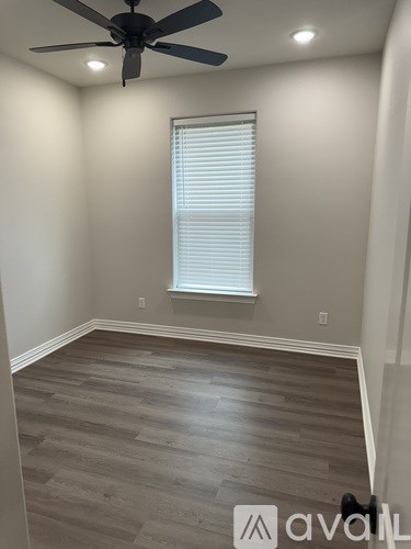 A room with a ceiling fan and a window with blinds.