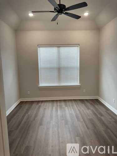 A room with a ceiling fan and a window with blinds.