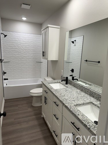 A bathroom with a white tub, toilet, and sink.