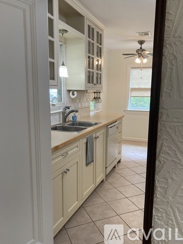 A kitchen with white cabinets and a fan on the ceiling.